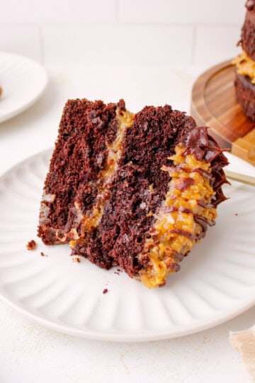 Slice of Homemade German chocolate cake with coconut pecan filling and ganache border.