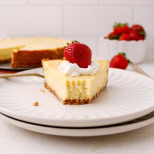 Plated classic cheesecake with strawberry and whipped cream on top.