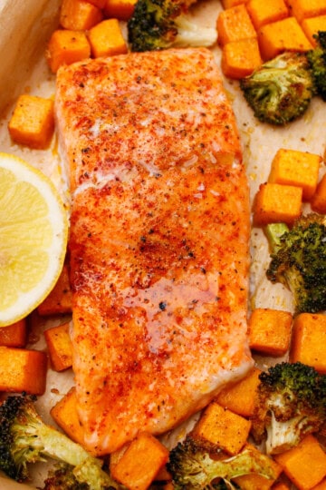 Baked salmon fillets, roasted butternut squash, and broccoli straight out of the oven on a sheet pan.